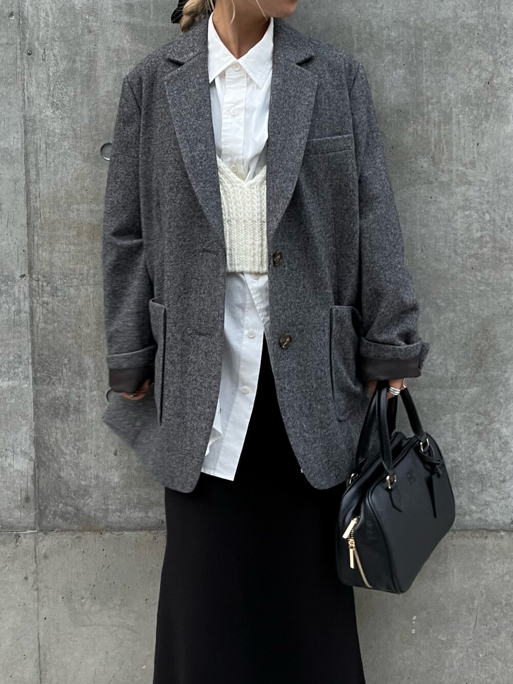 ブラック系のハンドバッグ、グレー系のテーラードジャケット、ブラック系のスカートを着用したレディースの冬コーディネートの2枚目の写真