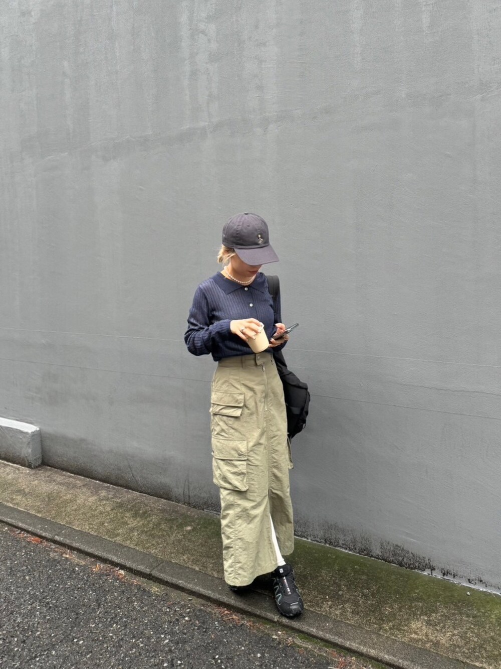 ブルー系のニット/セーター、グリーン系のスカート、グレー系のキャップを着用したレディースの春コーディネートの2枚目の写真