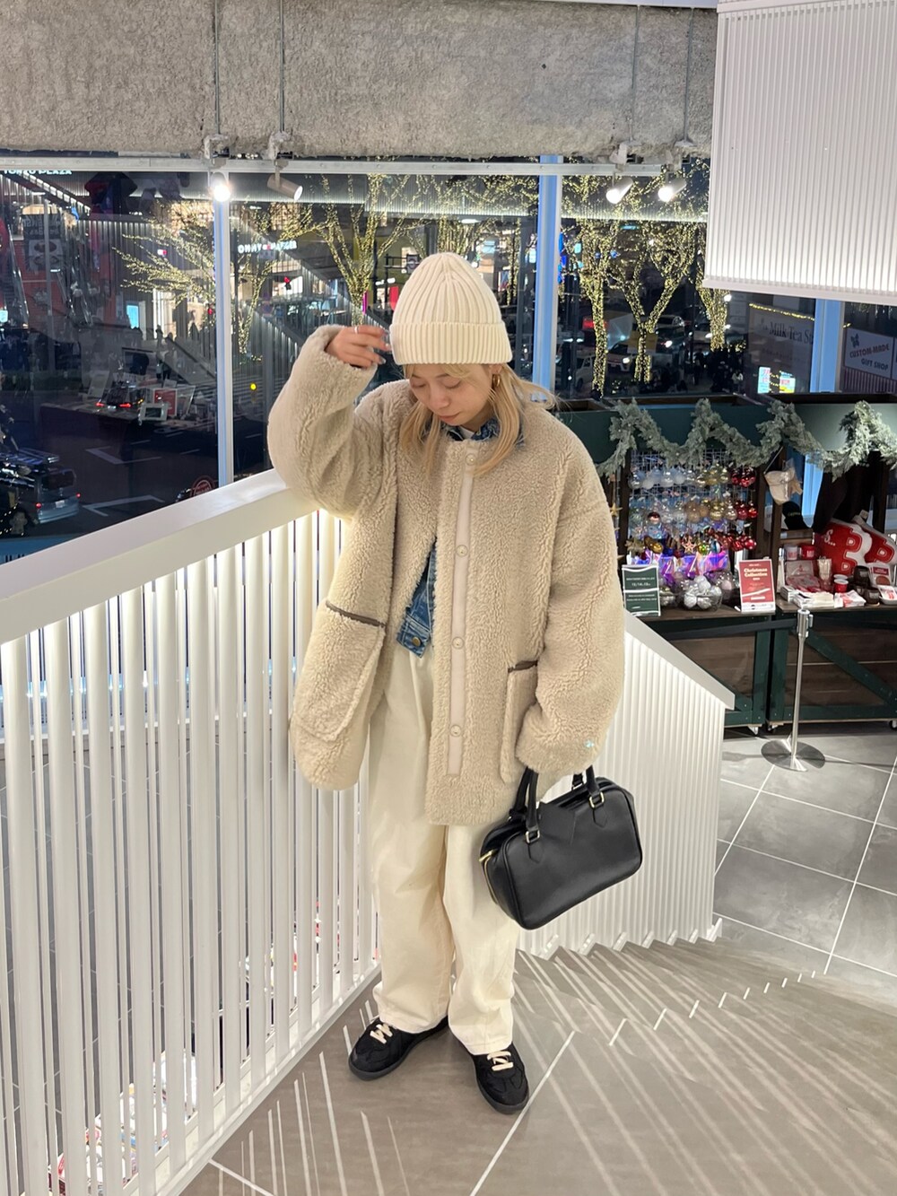 ベージュ系のノーカラーコート、ホワイト系のその他パンツ、ブラック系のハンドバッグを着用したレディースの冬コーディネートの2枚目の写真