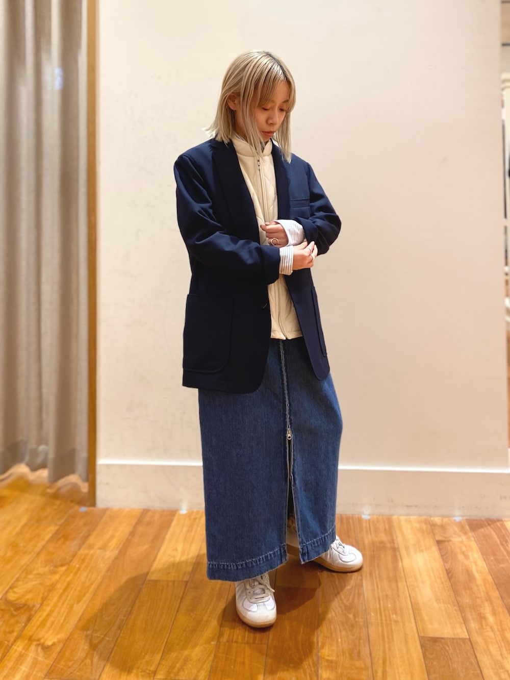 ブルー系のデニムスカート、ブルー系のテーラードジャケット、ホワイト系のダウンベストを着用したレディースの冬コーディネートの2枚目の写真