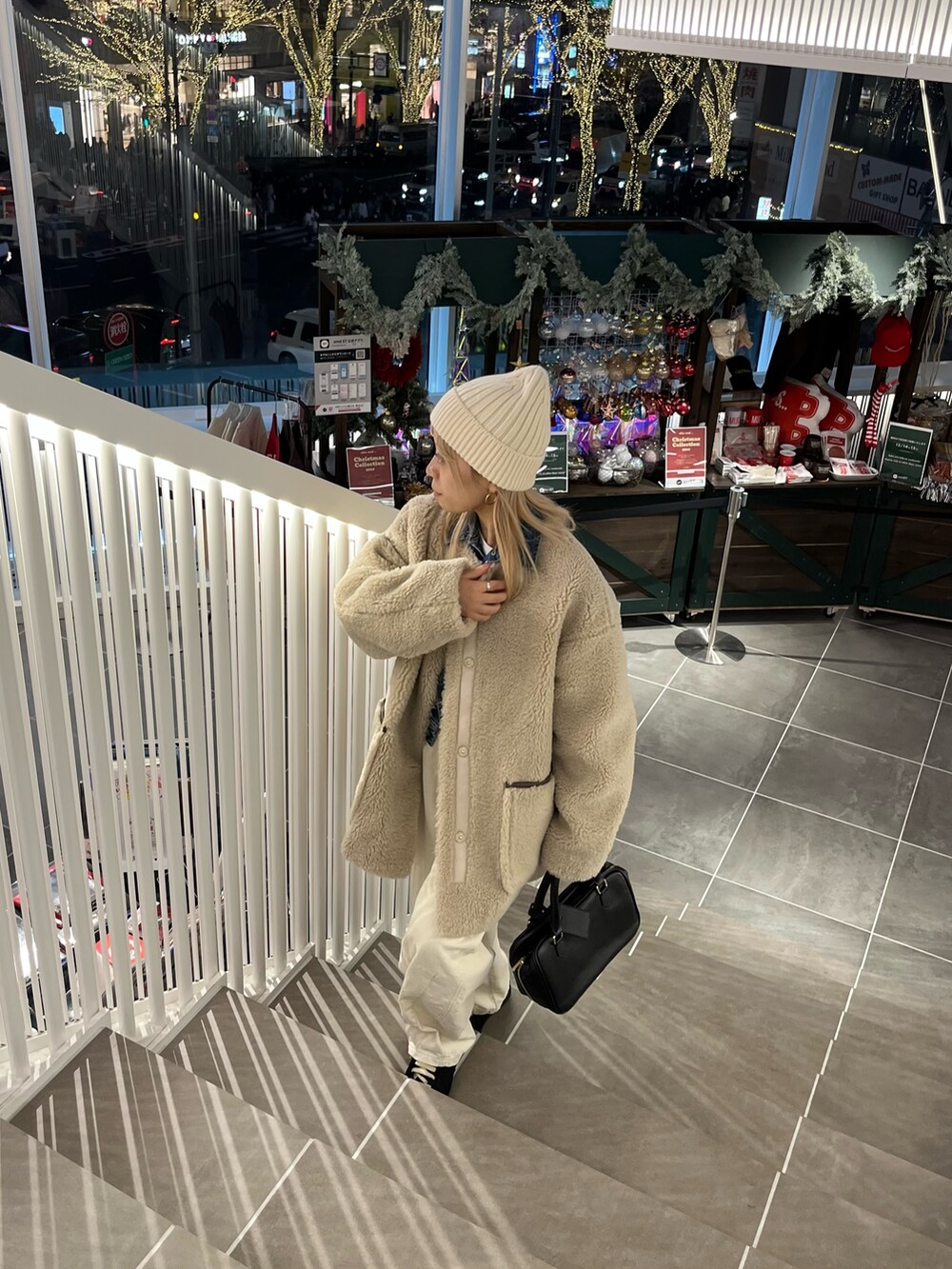 ベージュ系のノーカラーコート、ホワイト系のその他パンツ、ブラック系のハンドバッグを着用したレディースの冬コーディネートの4枚目の写真