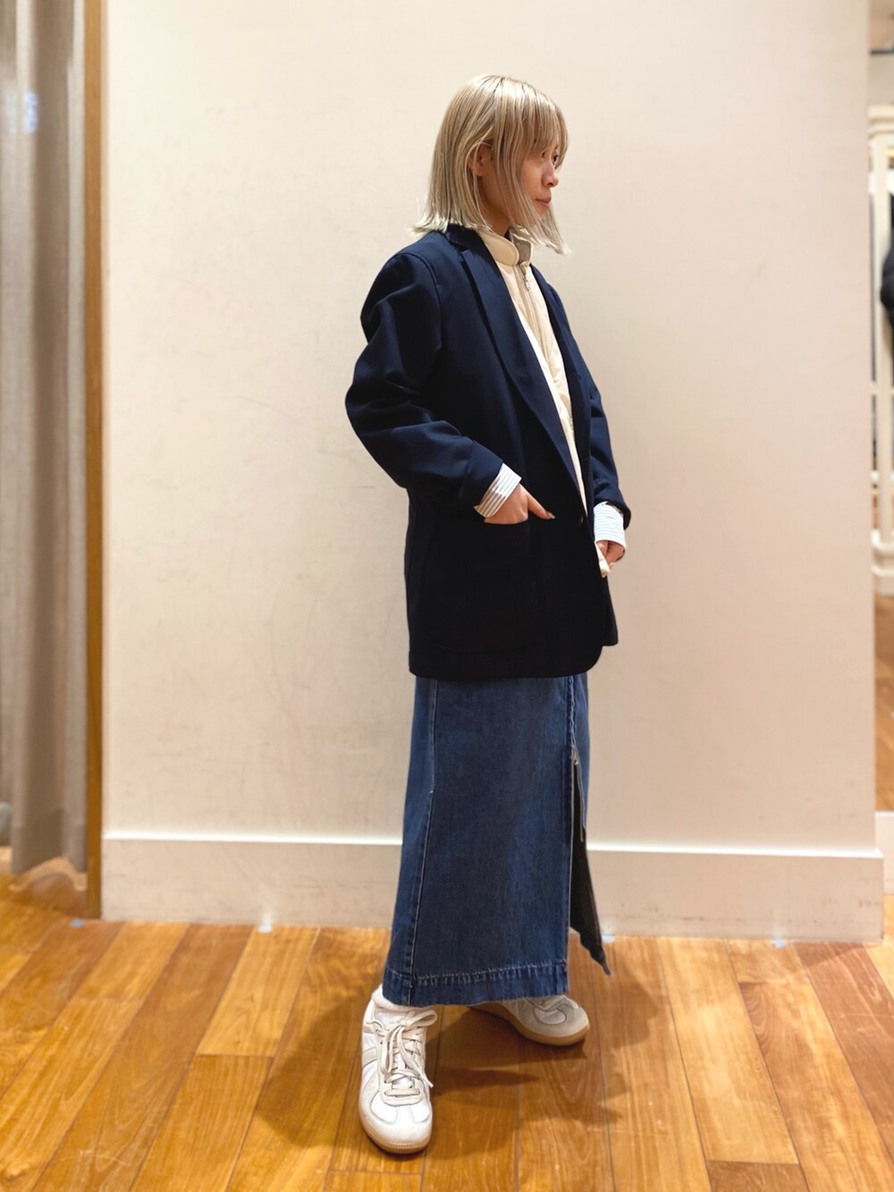 ブルー系のデニムスカート、ブルー系のテーラードジャケット、ホワイト系のダウンベストを着用したレディースの冬コーディネートの3枚目の写真