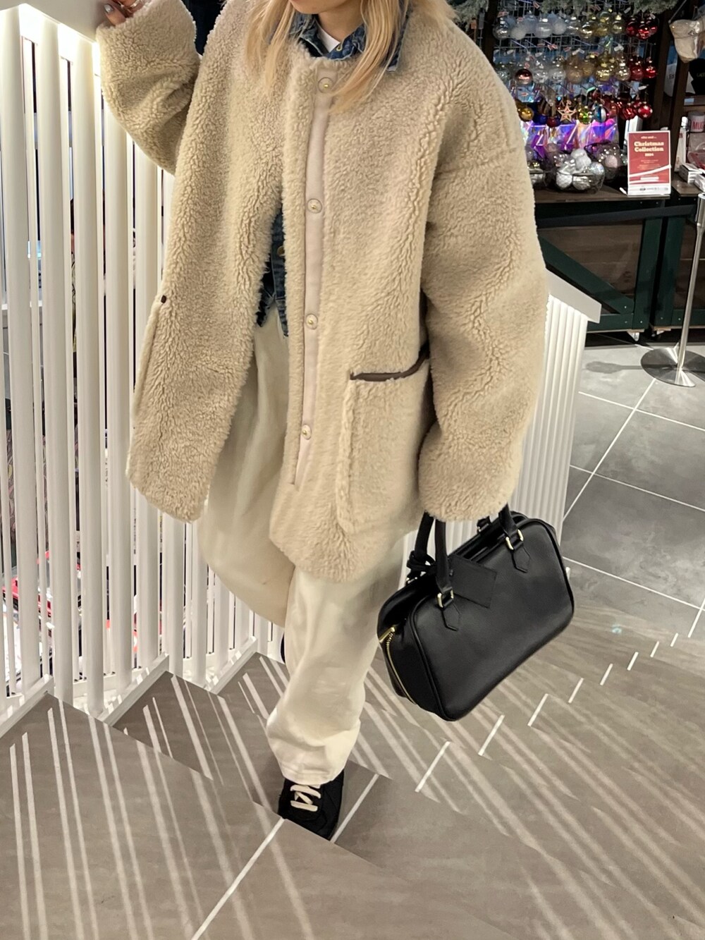 ベージュ系のノーカラーコート、ホワイト系のその他パンツ、ブラック系のハンドバッグを着用したレディースの冬コーディネートの3枚目の写真