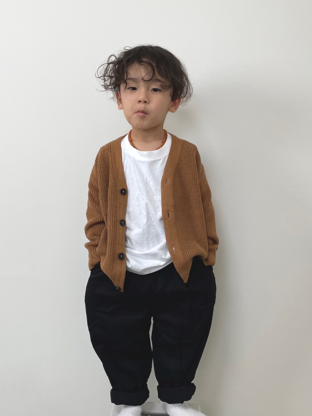 ブラック系のチノパンツ、ホワイト系のTシャツ/カットソー、ブラウン系のカーディガン/ボレロを着用したキッズの冬コーディネートの2枚目の写真