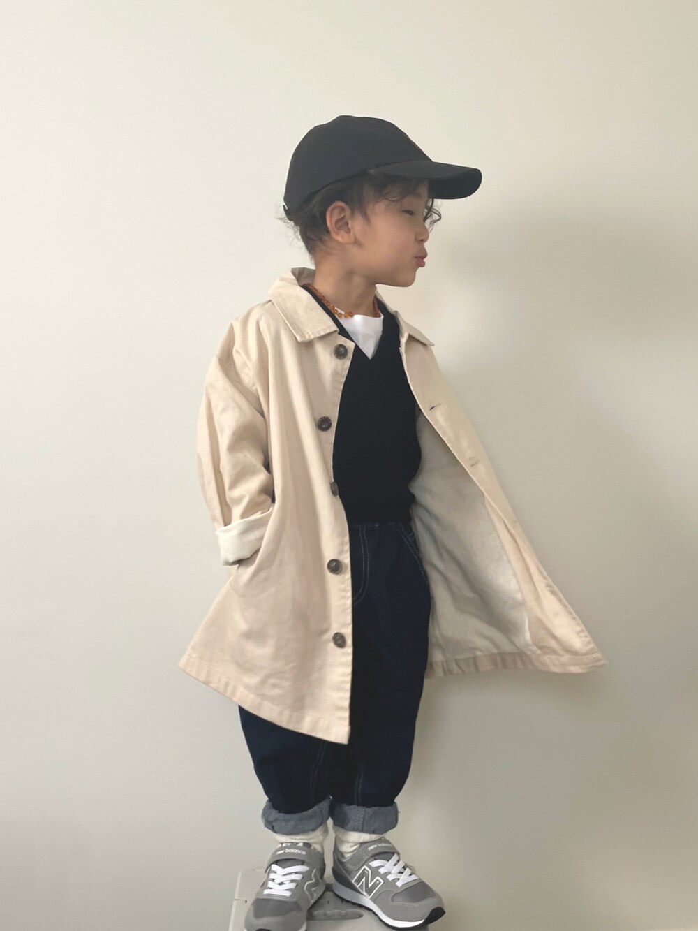 ブルー系のデニムパンツ、グレー系のスニーカー、ベージュ系のステンカラーコートを着用したキッズの冬コーディネートの2枚目の写真