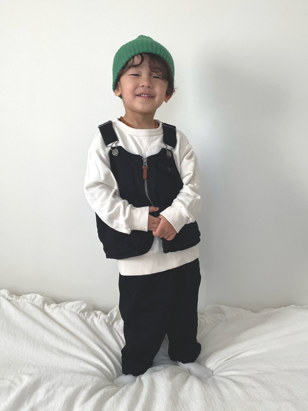 ブラック系のベスト、ブラック系のチノパンツ、ホワイト系のスウェットを着用したキッズの冬コーディネートの2枚目の写真