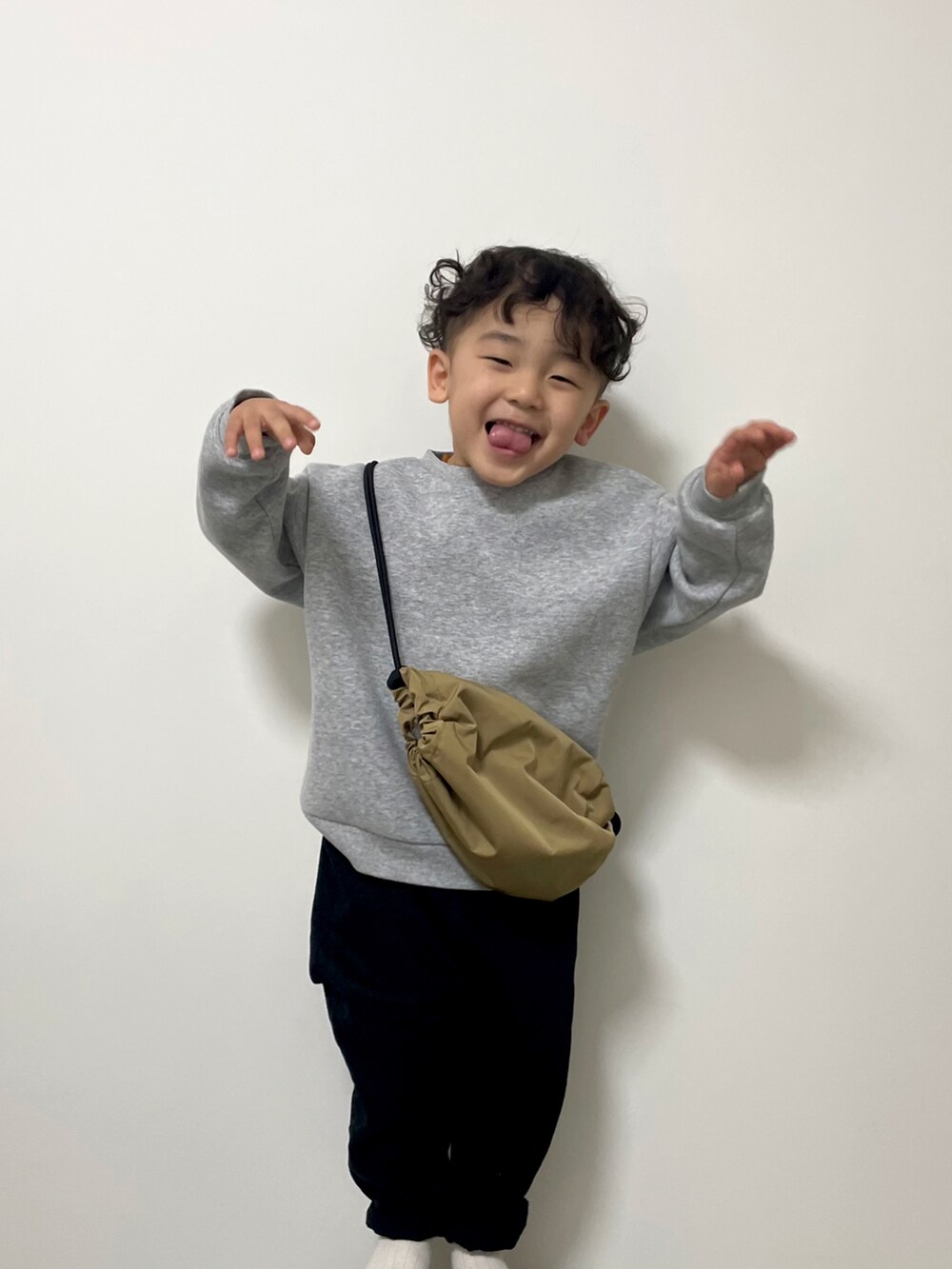 グレー系のスウェット、ベージュ系のボディバッグ/ウエストポーチ、ブラック系のチノパンツを着用したキッズの春コーディネートの3枚目の写真