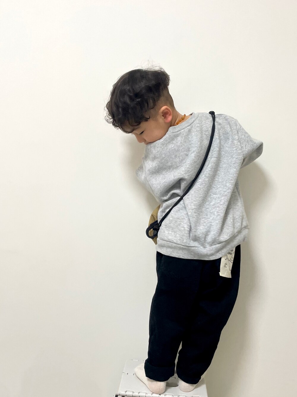 グレー系のスウェット、ベージュ系のボディバッグ/ウエストポーチ、ブラック系のチノパンツを着用したキッズの春コーディネートの2枚目の写真
