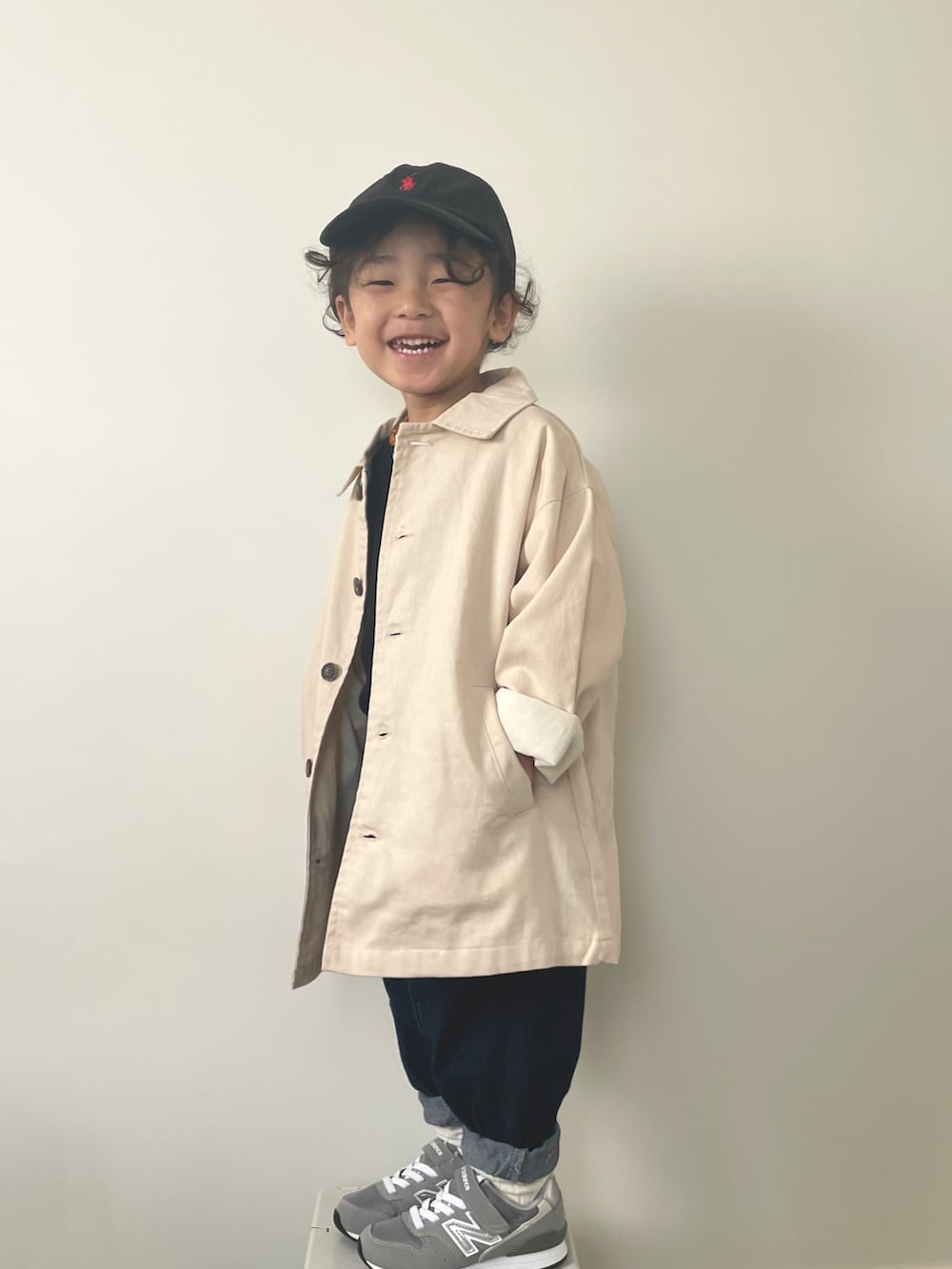 ブルー系のデニムパンツ、グレー系のスニーカー、ベージュ系のステンカラーコートを着用したキッズの冬コーディネートの3枚目の写真