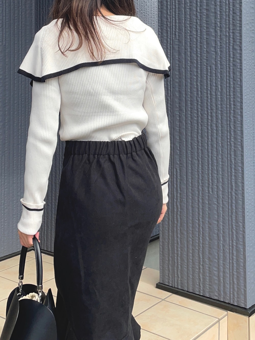 ブラック系のスカート、ブラック系のブーツ、ホワイト系のニット/セーターを着用したレディースの冬コーディネートの3枚目の写真