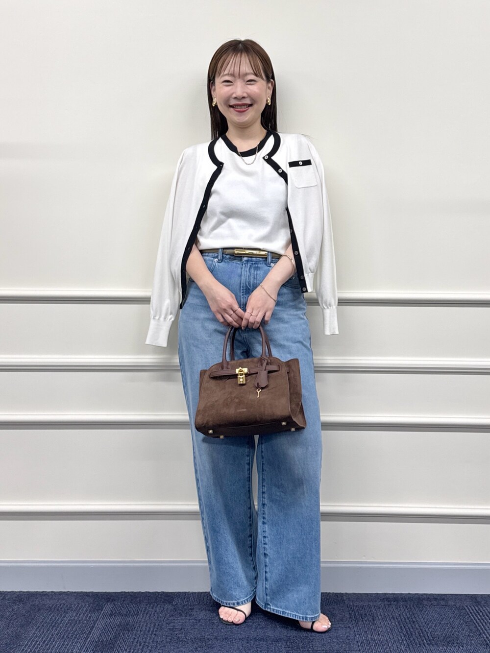 ブルー系のデニムパンツ、ブラウン系のトートバッグ、ホワイト系のカーディガン/ボレロを着用したレディースの夏コーディネートの2枚目の写真