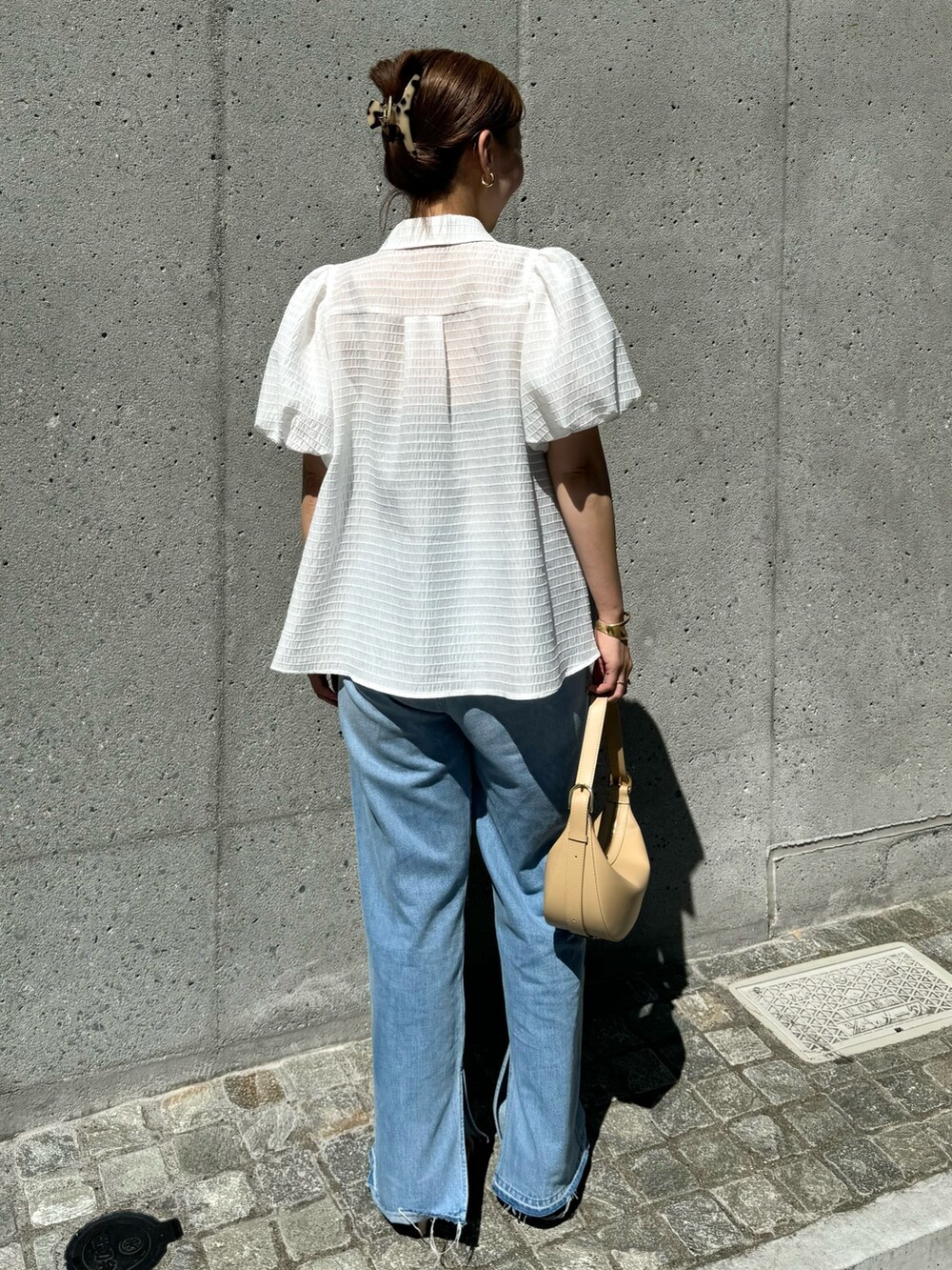 ホワイト系のシャツ/ブラウス、ベージュ系のショルダーバッグ、ブルー系のデニムパンツを着用したレディースの夏コーディネートの7枚目の写真