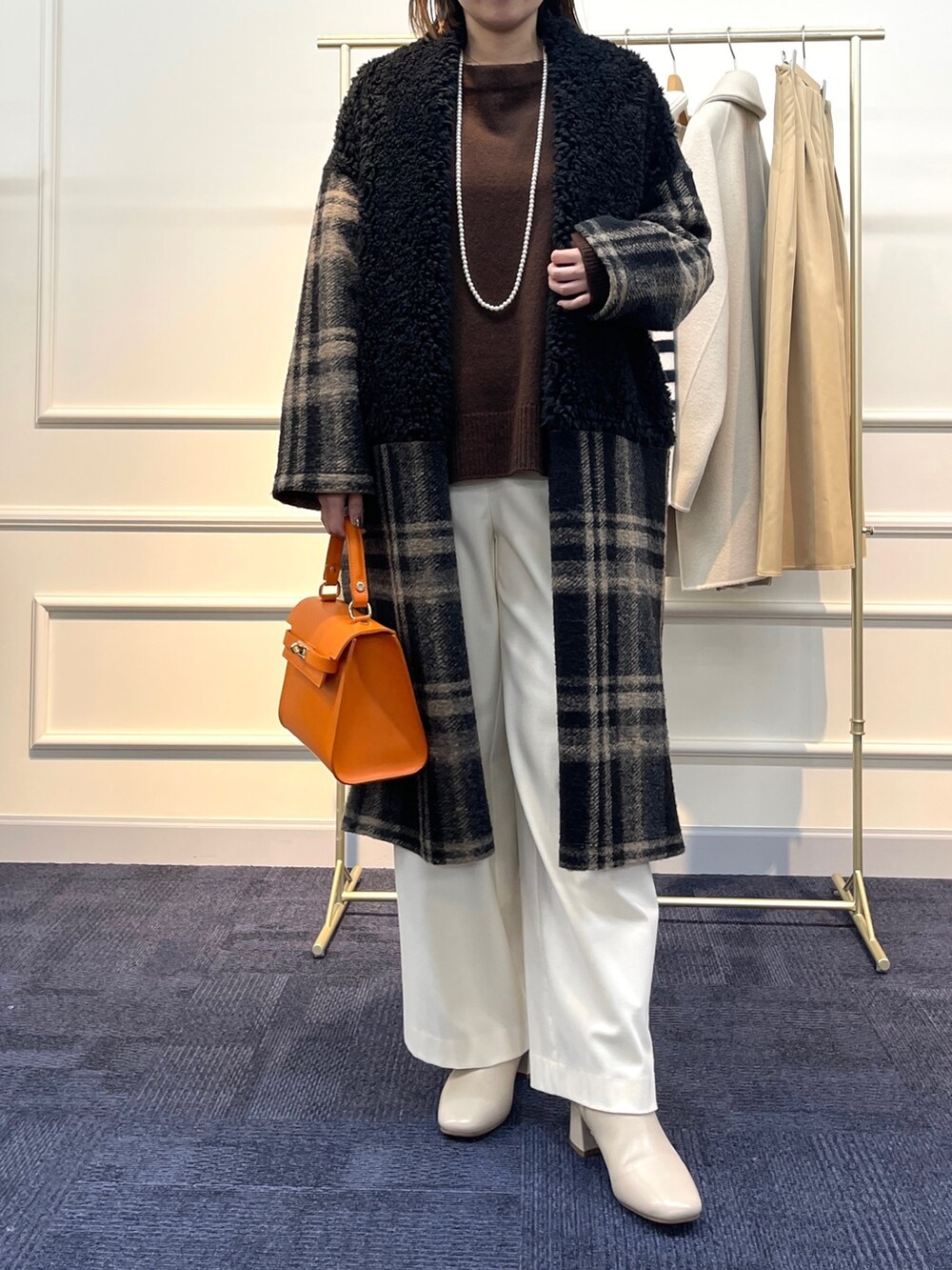 ブラウン系のニット/セーター、ブラック系のその他アウター、オレンジ系のショルダーバッグを着用したレディースの冬コーディネートの2枚目の写真
