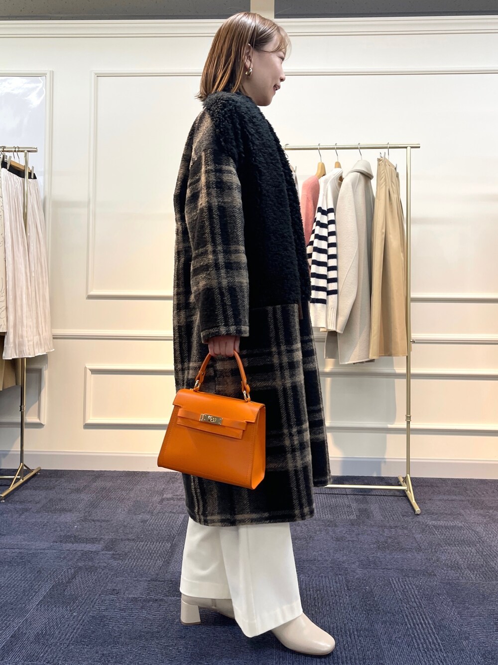 ブラウン系のニット/セーター、ブラック系のその他アウター、オレンジ系のショルダーバッグを着用したレディースの冬コーディネートの5枚目の写真