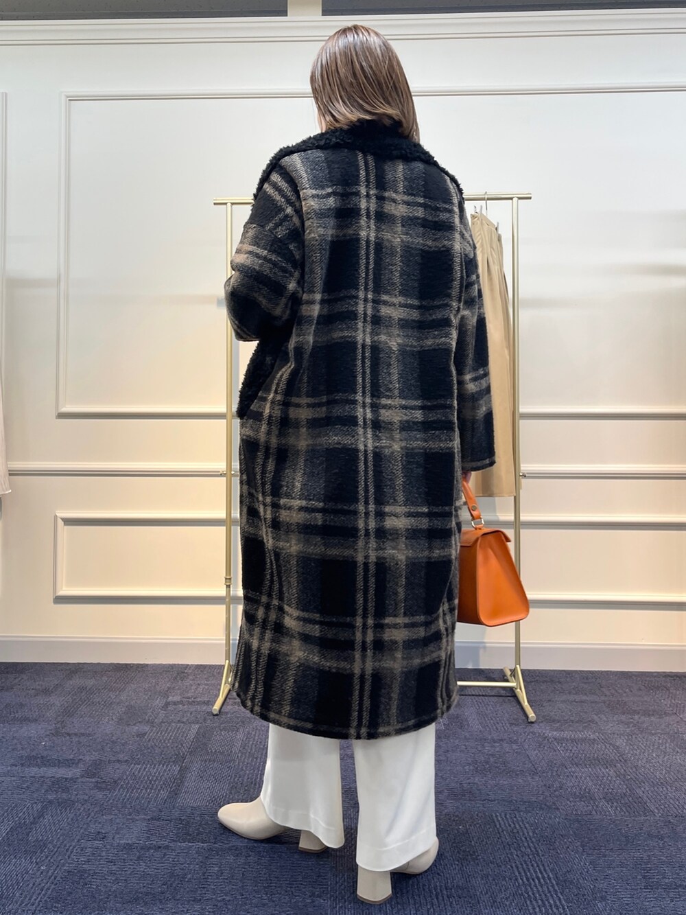 ブラウン系のニット/セーター、ブラック系のその他アウター、オレンジ系のショルダーバッグを着用したレディースの冬コーディネートの6枚目の写真