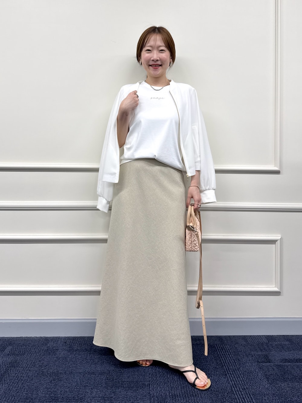 ベージュ系のスカート、ホワイト系のブルゾン、ホワイト系のTシャツ/カットソーを着用したレディースの夏コーディネートの5枚目の写真