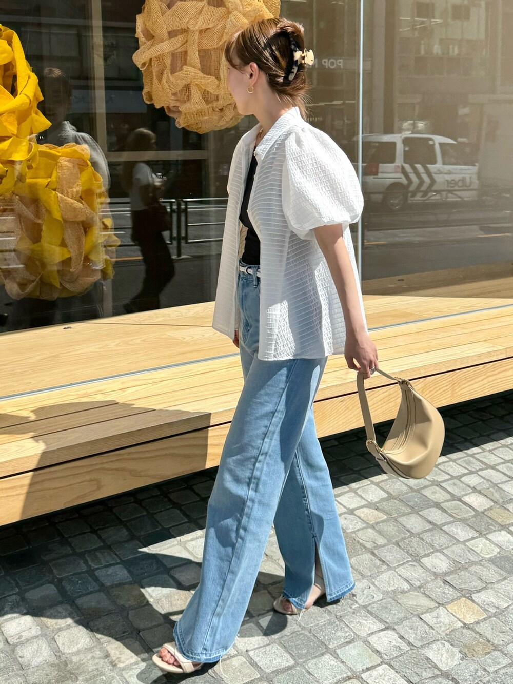 ホワイト系のシャツ/ブラウス、ベージュ系のショルダーバッグ、ブルー系のデニムパンツを着用したレディースの夏コーディネートの5枚目の写真