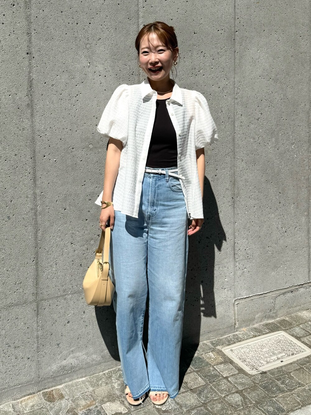 ホワイト系のシャツ/ブラウス、ベージュ系のショルダーバッグ、ブルー系のデニムパンツを着用したレディースの夏コーディネートの2枚目の写真