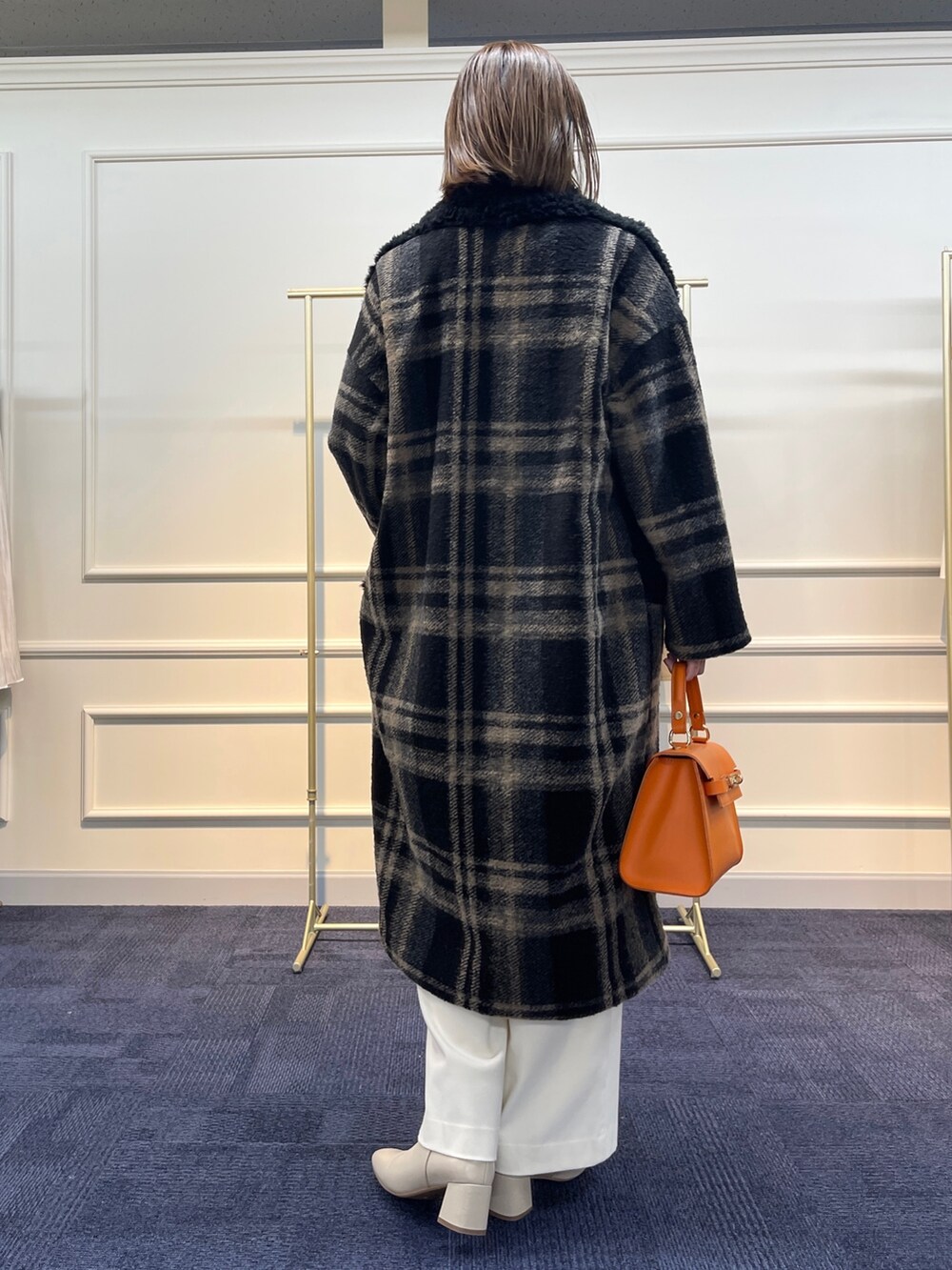 ブラウン系のニット/セーター、ブラック系のその他アウター、オレンジ系のショルダーバッグを着用したレディースの冬コーディネートの7枚目の写真