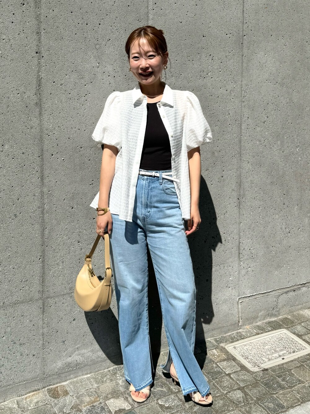 ホワイト系のシャツ/ブラウス、ベージュ系のショルダーバッグ、ブルー系のデニムパンツを着用したレディースの夏コーディネートの3枚目の写真