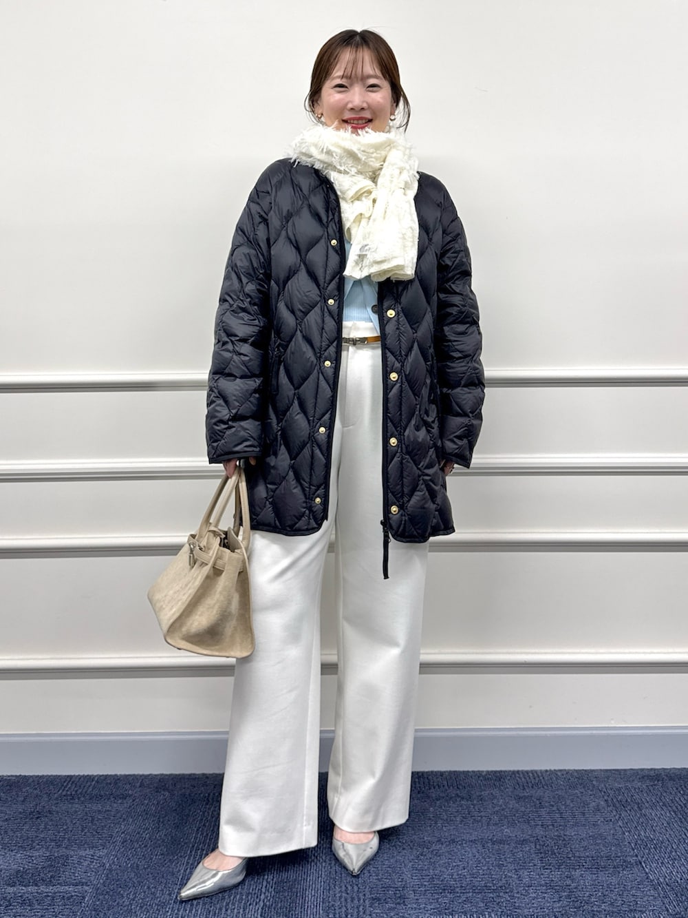 ホワイト系のその他パンツ、ブラウン系のトートバッグ、ブラック系のダウンジャケット/コートを着用したレディースの秋コーディネートの3枚目の写真