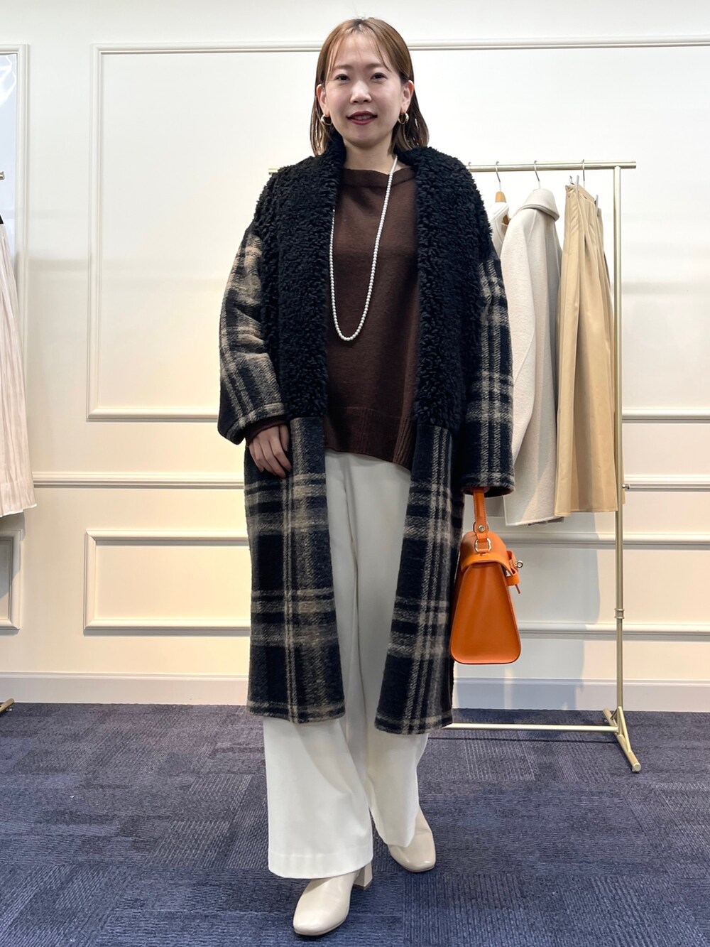 ブラウン系のニット/セーター、ブラック系のその他アウター、オレンジ系のショルダーバッグを着用したレディースの冬コーディネートの3枚目の写真