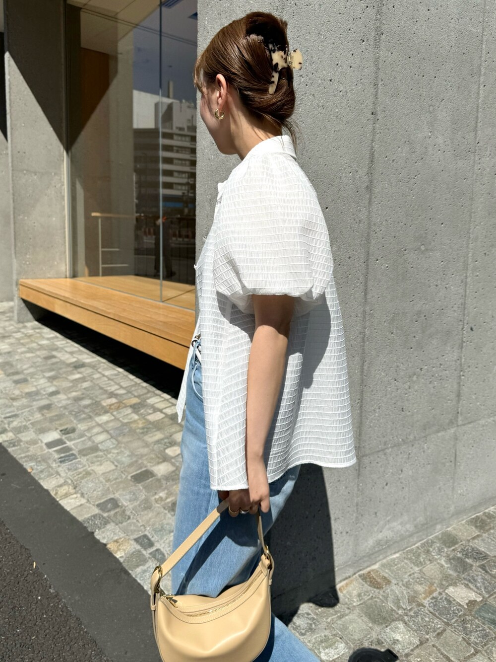 ホワイト系のシャツ/ブラウス、ベージュ系のショルダーバッグ、ブルー系のデニムパンツを着用したレディースの夏コーディネートの8枚目の写真