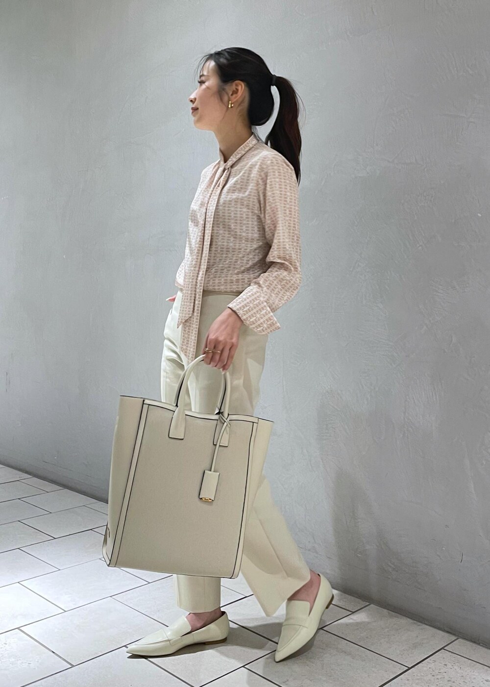 ベージュ系のトートバッグ、ピンク系のシャツ/ブラウス、ホワイト系のパンプスを着用したレディースの冬コーディネートの3枚目の写真