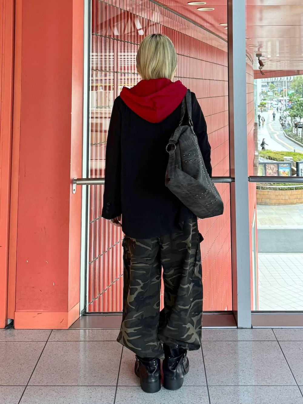 レッド系のパーカー、ブラック系のテーラードジャケット、ブラック系のブーツを着用したレディースの春コーディネートの3枚目の写真