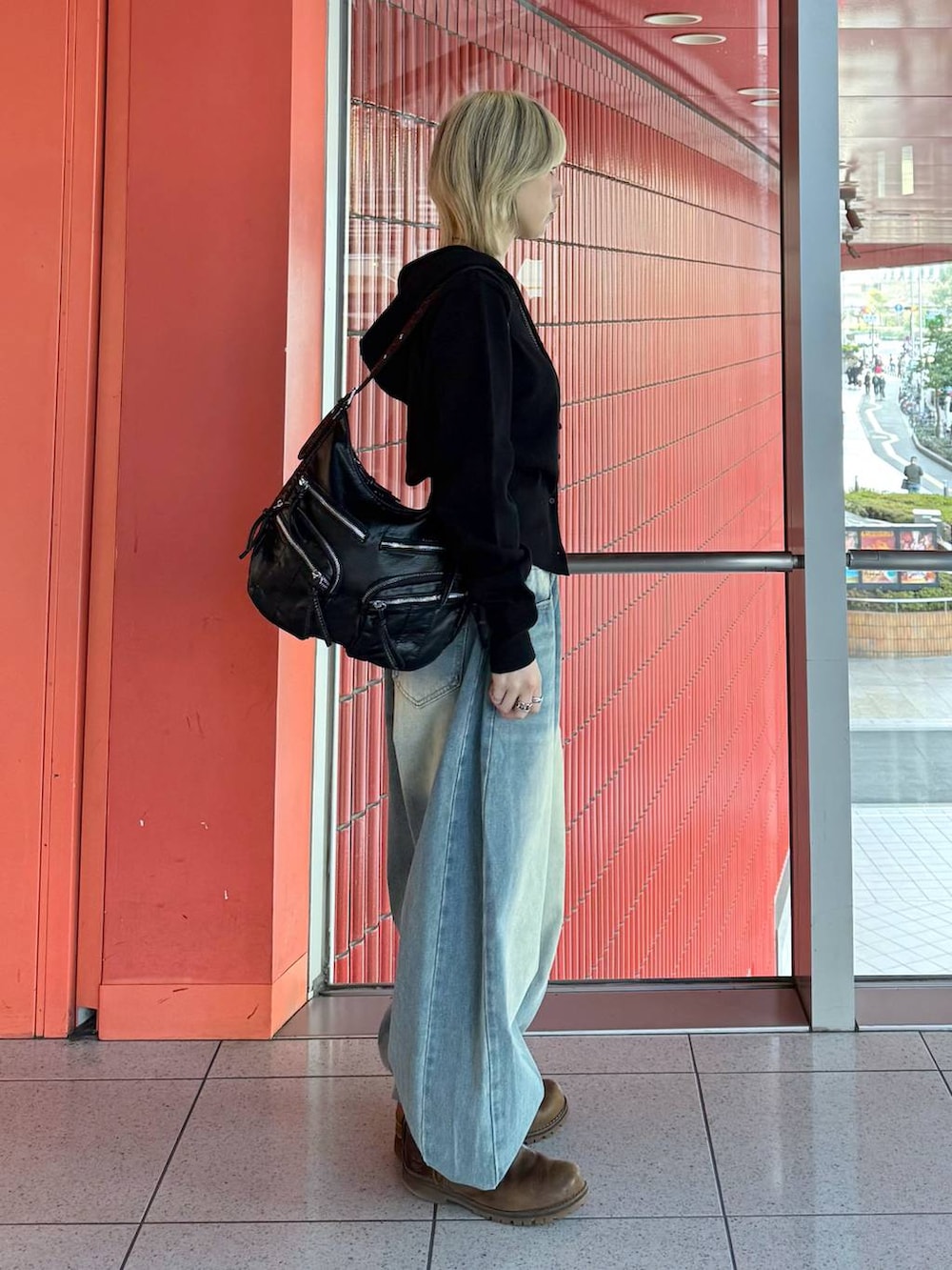 ブラック系のショルダーバッグ、ブルー系のデニムパンツ、ブラック系のニット/セーターを着用したレディースの冬コーディネートの2枚目の写真