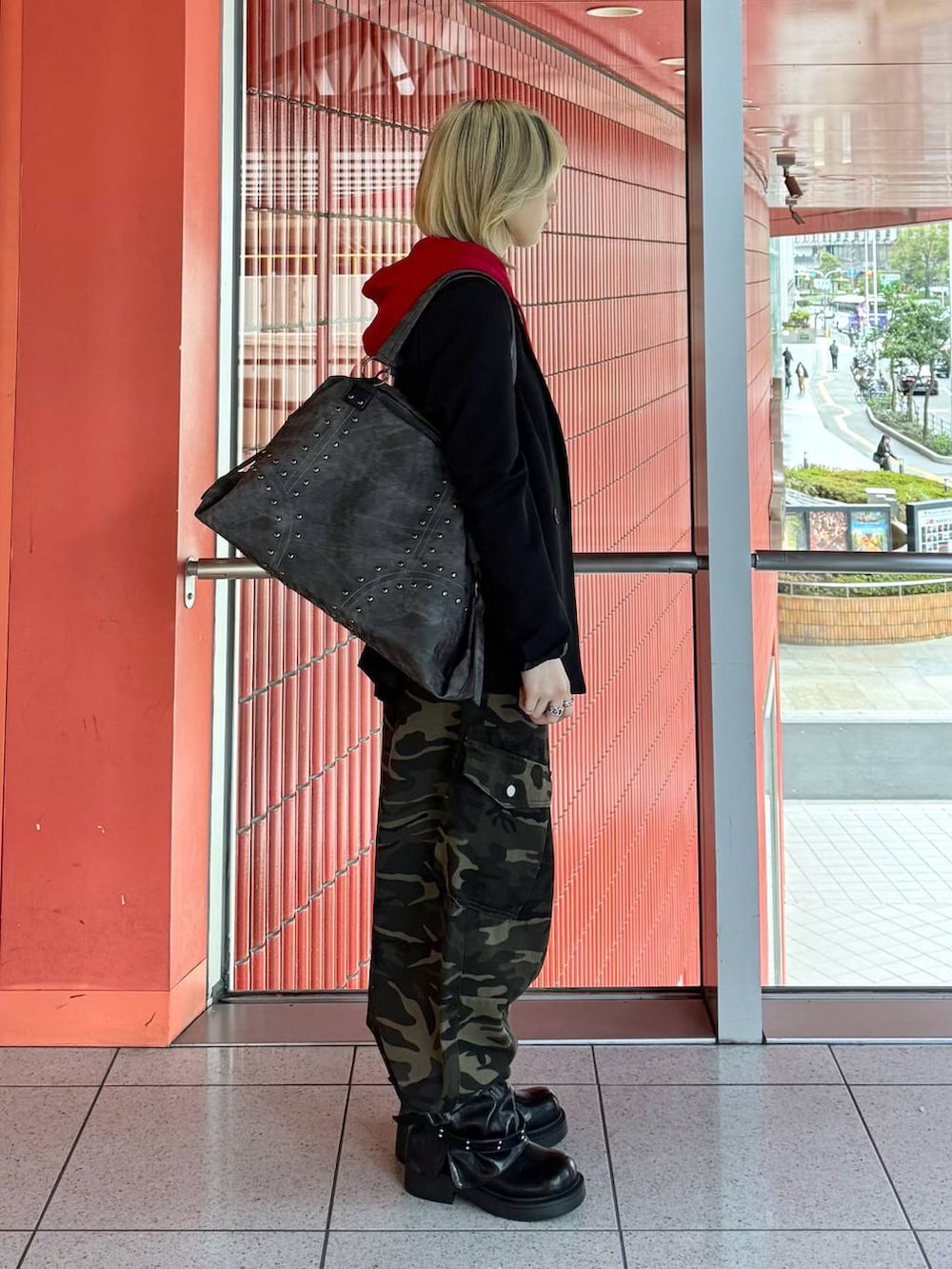 レッド系のパーカー、ブラック系のテーラードジャケット、ブラック系のブーツを着用したレディースの春コーディネートの4枚目の写真