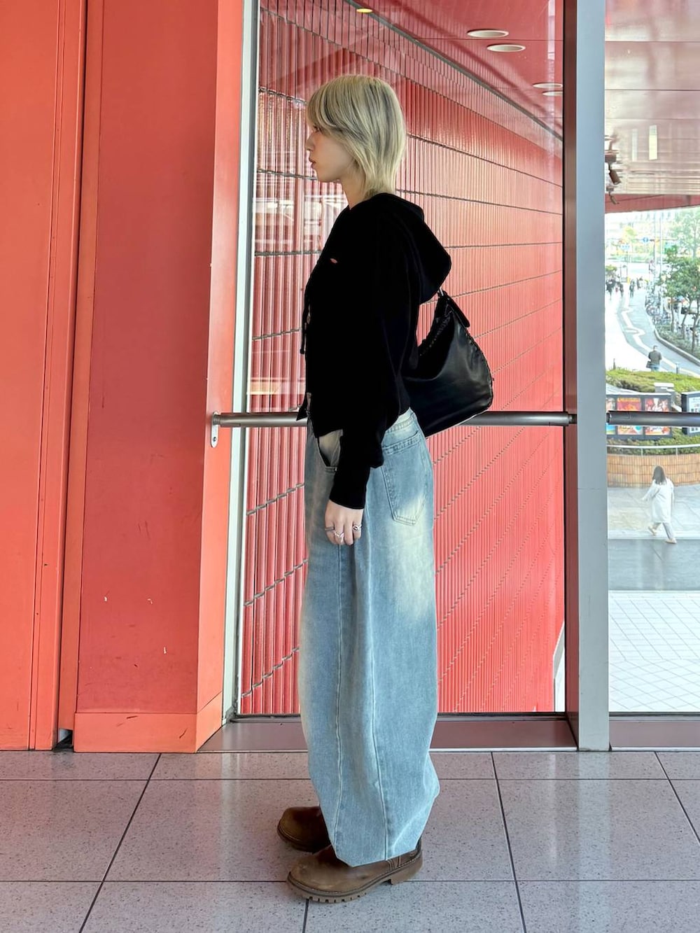 ブラック系のショルダーバッグ、ブルー系のデニムパンツ、ブラック系のニット/セーターを着用したレディースの冬コーディネートの4枚目の写真