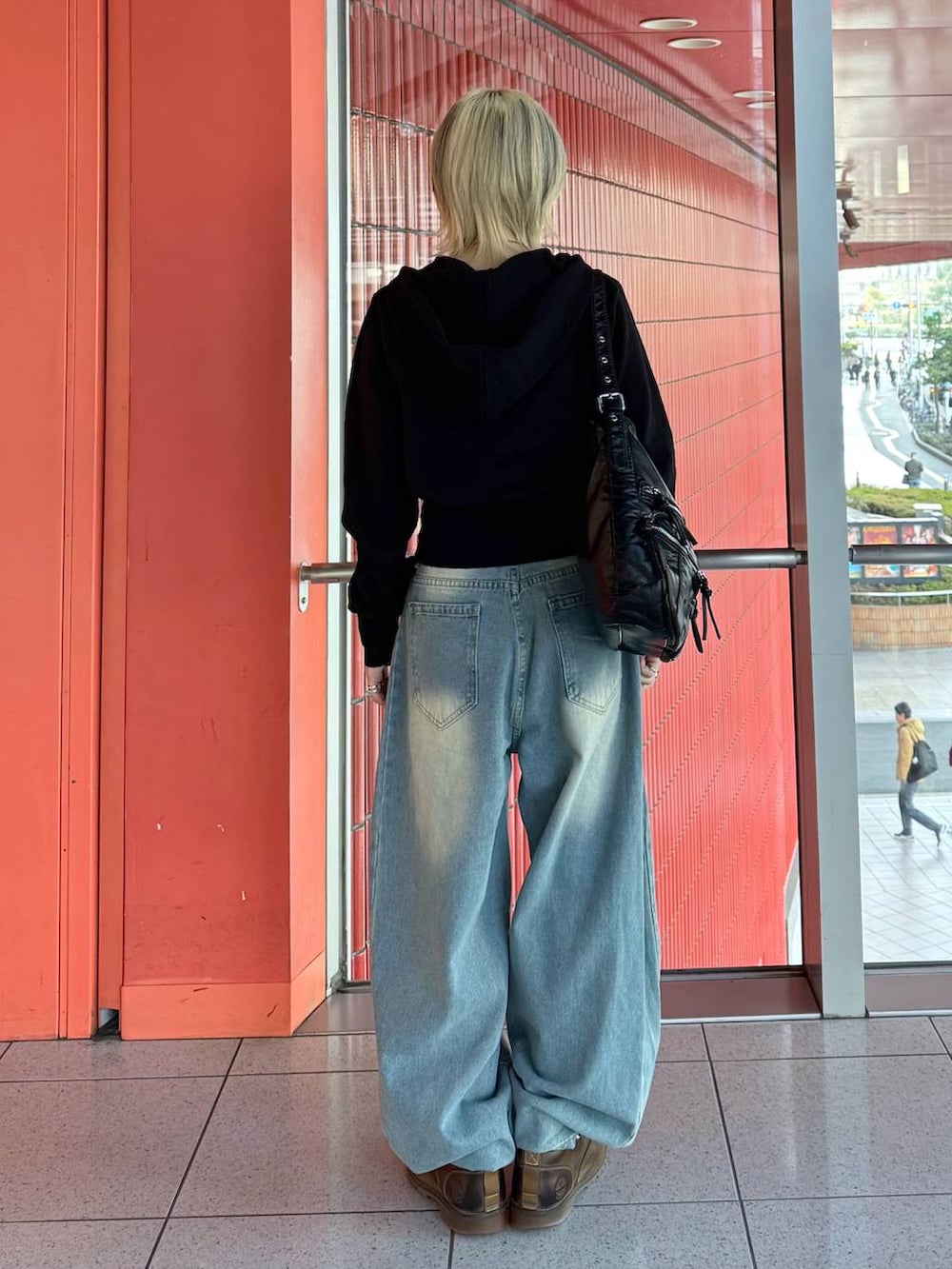 ブラック系のショルダーバッグ、ブルー系のデニムパンツ、ブラック系のニット/セーターを着用したレディースの冬コーディネートの3枚目の写真