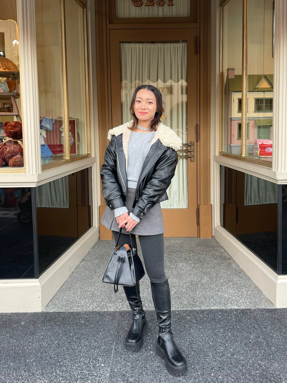 グレー系のニット/セーター、ブラック系のライダースジャケット、グレー系のスカートを着用したレディースの冬コーディネートの2枚目の写真