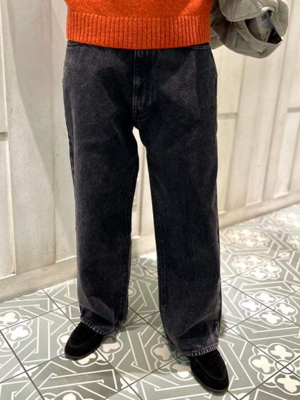 ブラック系のその他パンツ、ベージュ系のダウンジャケット/コート、オレンジ系のニット/セーターを着用したメンズの冬コーディネートの7枚目の写真