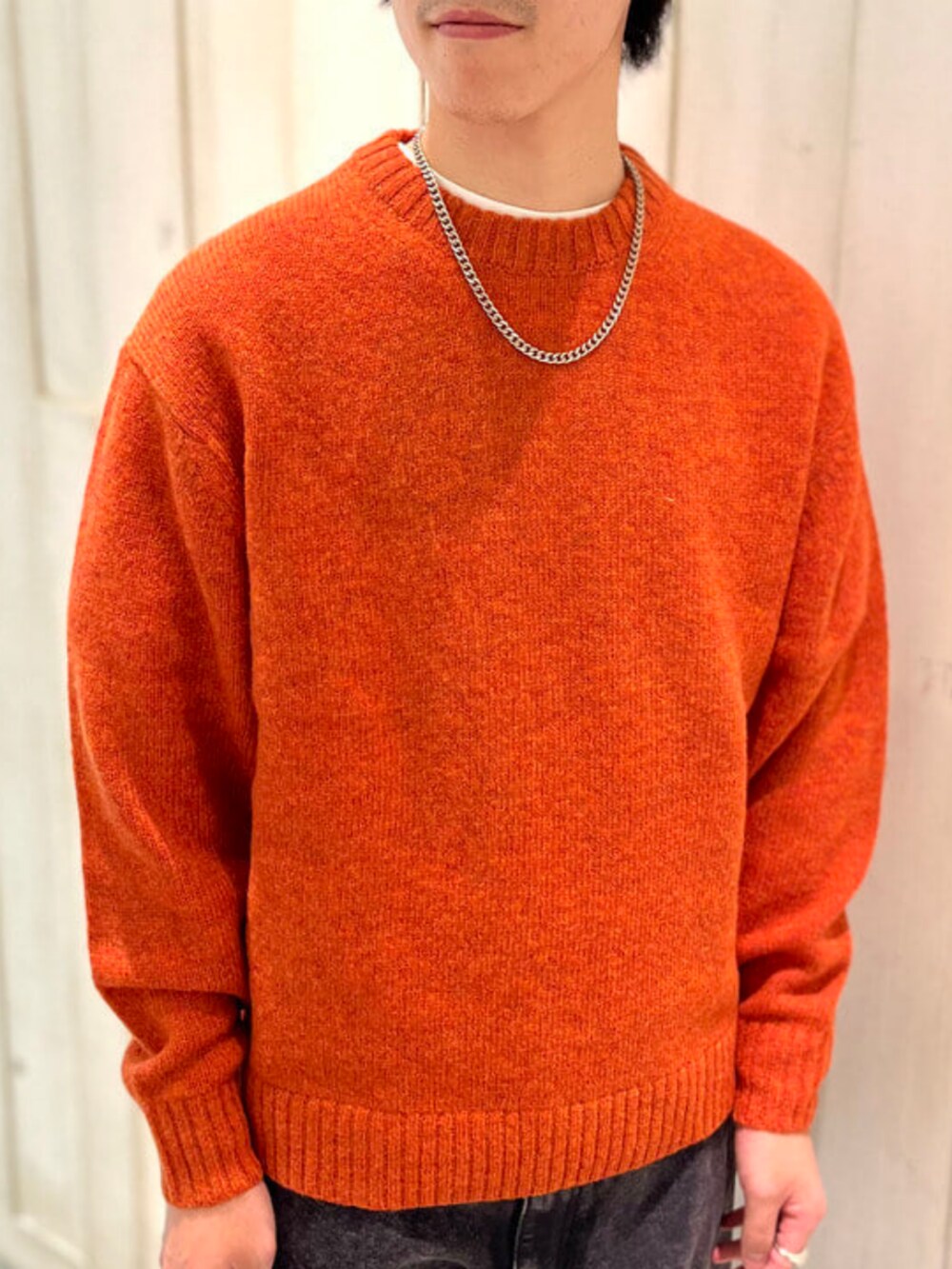 ブラック系のその他パンツ、ベージュ系のダウンジャケット/コート、オレンジ系のニット/セーターを着用したメンズの冬コーディネートの6枚目の写真