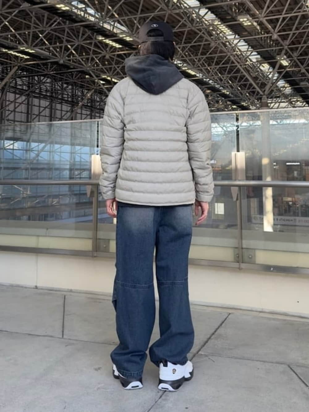 ブラック系のパーカー、ベージュ系のダウンジャケット/コート、ブルー系のデニムパンツを着用したメンズの冬コーディネートの2枚目の写真