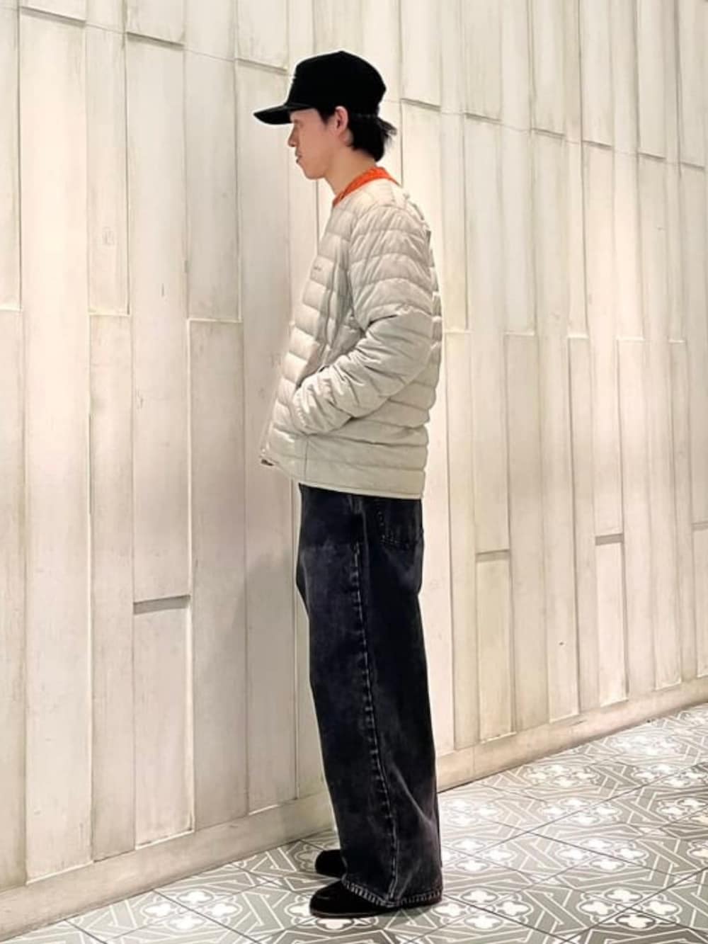 ブラック系のその他パンツ、ベージュ系のダウンジャケット/コート、オレンジ系のニット/セーターを着用したメンズの冬コーディネートの2枚目の写真