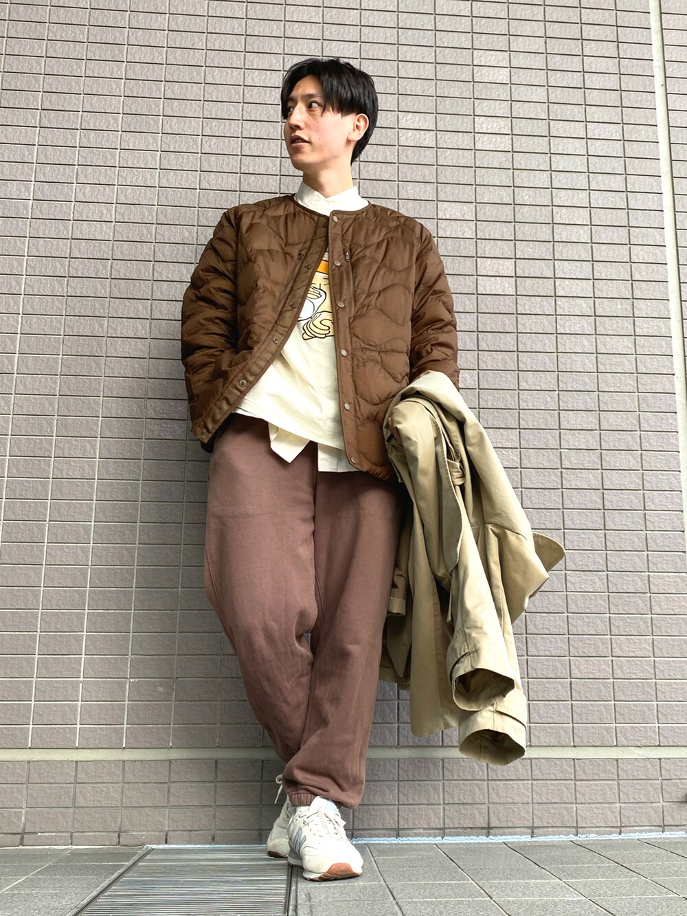 ベージュ系のトレンチコート、ブラウン系のスウェットパンツ、ホワイト系のスニーカーを着用したメンズの冬コーディネートの2枚目の写真
