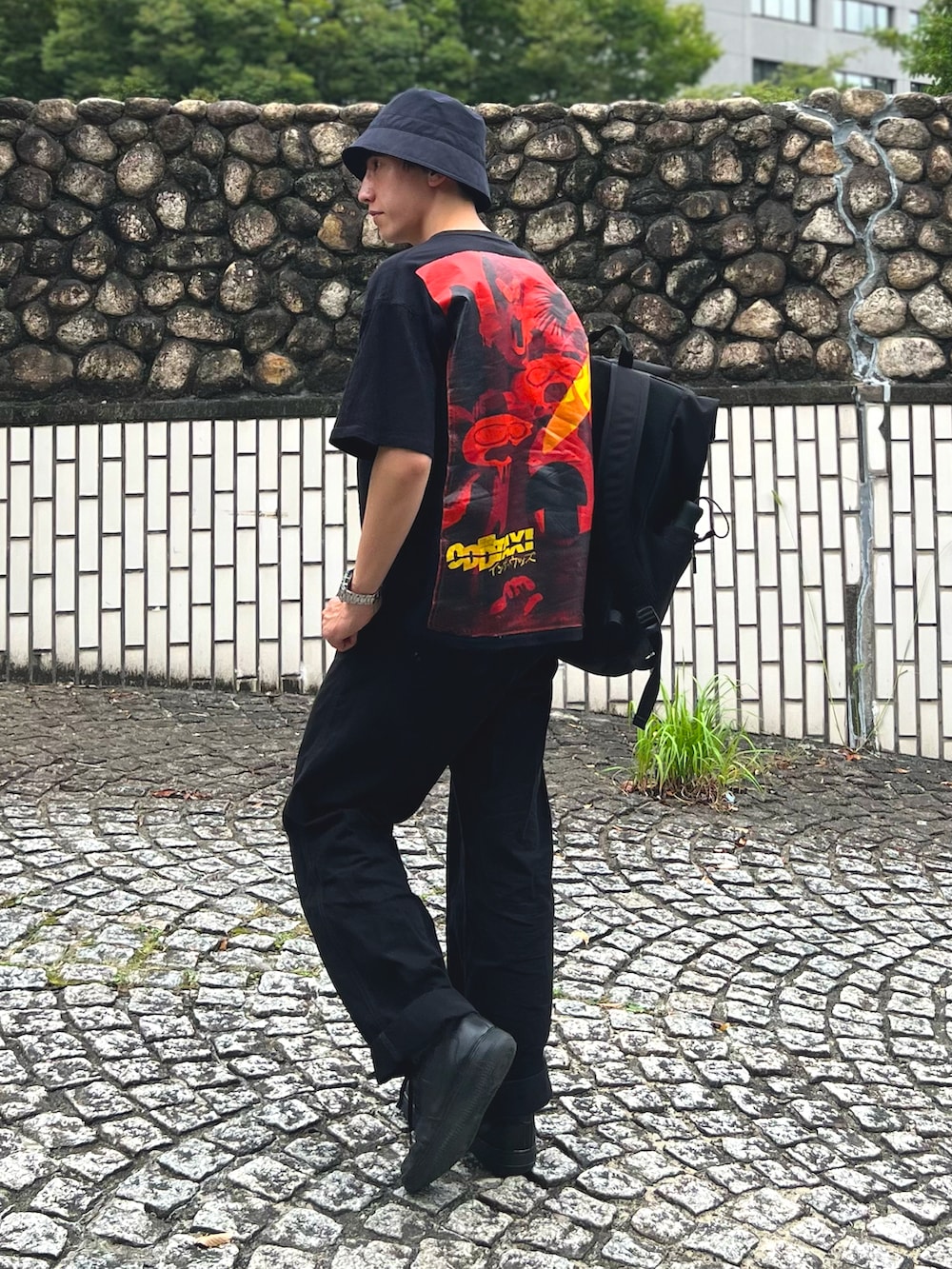 ブラック系のTシャツ/カットソー、ブラック系のバックパック/リュック、ブラック系のデニムパンツを着用したメンズの秋コーディネートの2枚目の写真