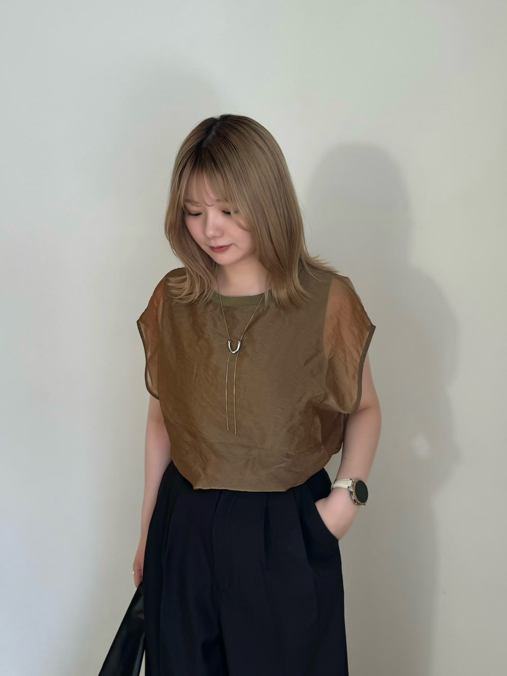 ブラック系のスラックス、ブラック系のサンダル、グリーン系のTシャツ/カットソーを着用したレディースの春コーディネートの3枚目の写真