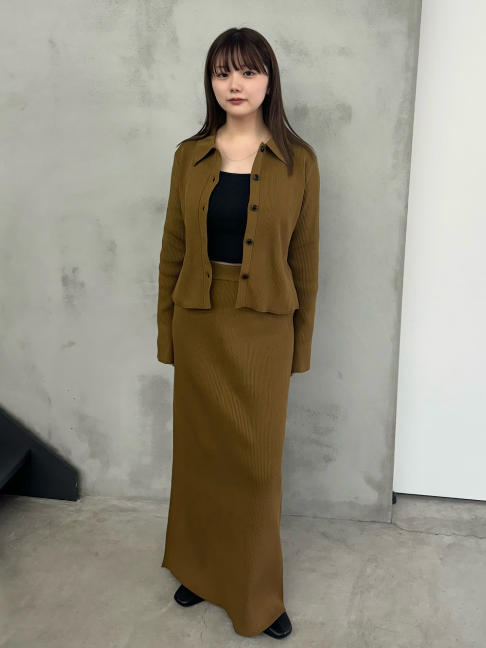 イエロー系のスカート、イエロー系のカーディガン/ボレロ、ブラック系のキャミソールを着用したレディースの冬コーディネートの2枚目の写真