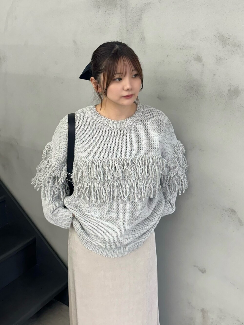 グレー系のニット/セーター、ホワイト系のスカート、ブラック系のショルダーバッグを着用したレディースの秋コーディネートの2枚目の写真