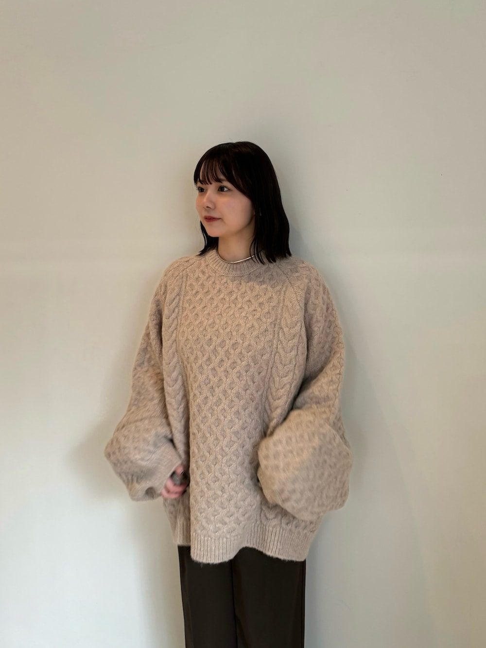 ベージュ系のニット/セーター、ブラウン系のスラックスを着用したレディースの秋コーディネートの2枚目の写真