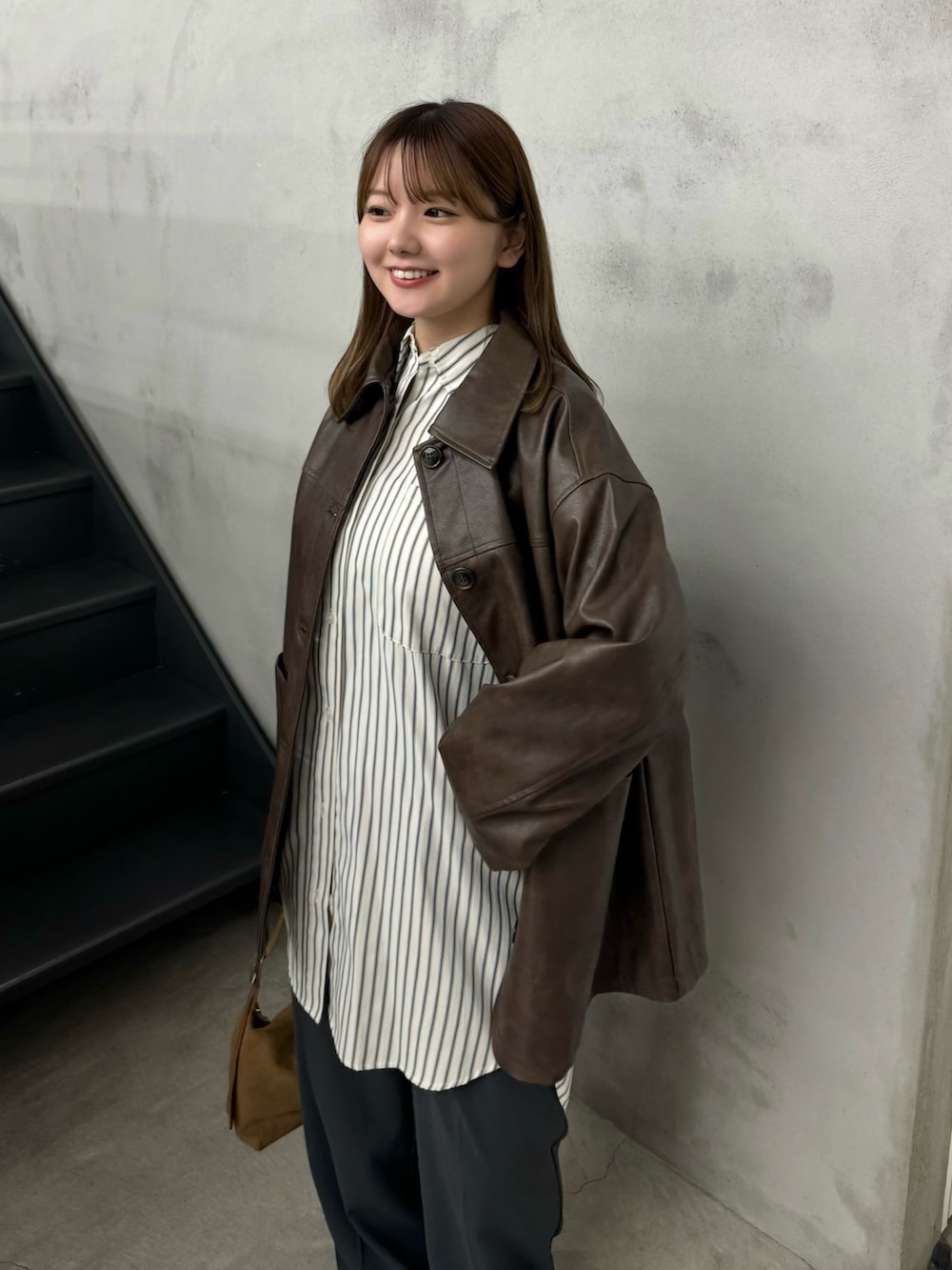 ブラウン系のステンカラーコート、ホワイト系のシャツ/ブラウス、グレー系のスラックスを着用したレディースの秋コーディネートの3枚目の写真
