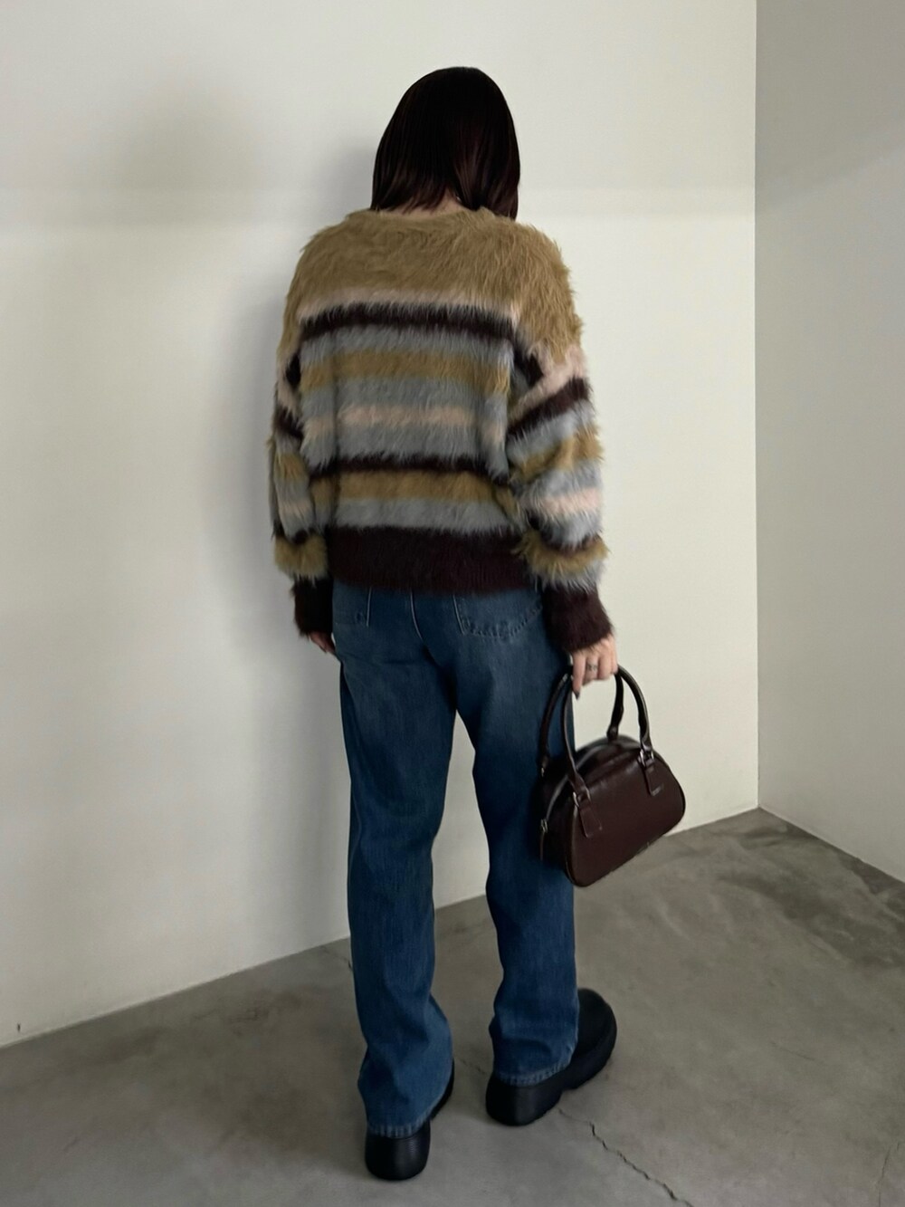 ブルー系のデニムパンツ、イエロー系のニット/セーター、ブラック系のブーツを着用したレディースの冬コーディネートの3枚目の写真