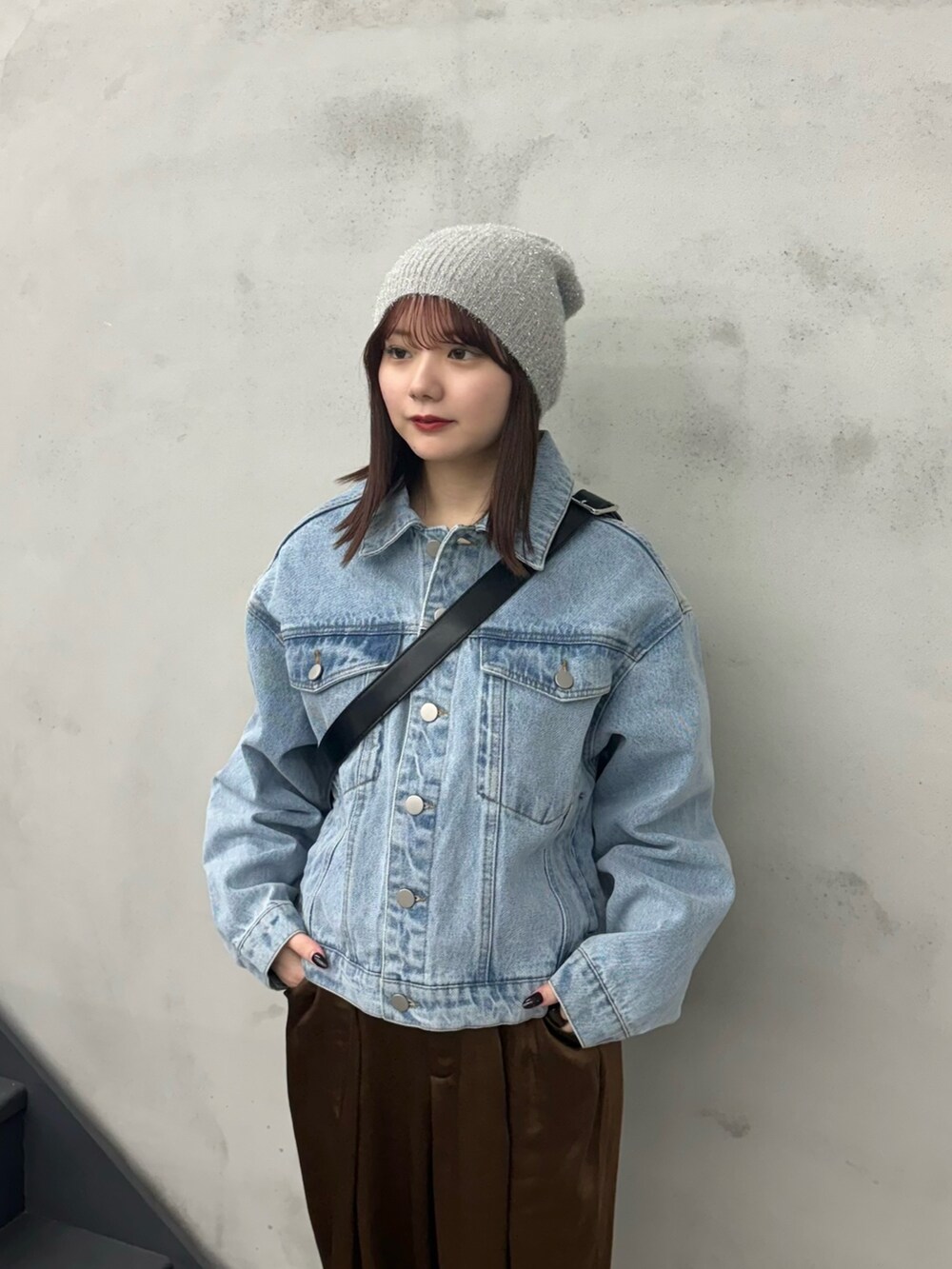 ブラウン系のスラックス、ブルー系のデニムジャケット、ブラック系のショルダーバッグを着用したレディースの冬コーディネートの4枚目の写真