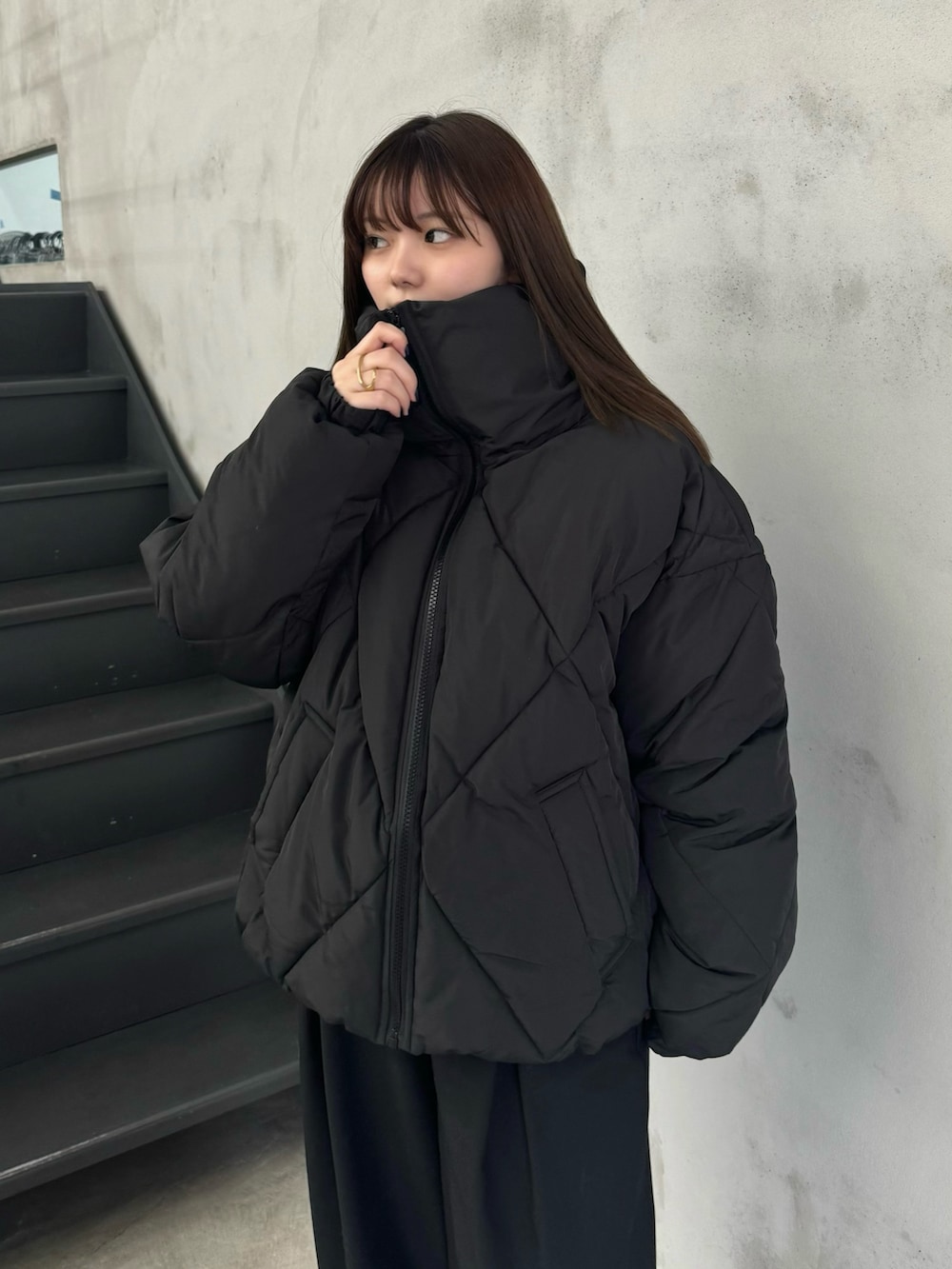 ピンク系のニット/セーター、ブラック系のダウンジャケット/コート、ブラック系のスラックスを着用したレディースの冬コーディネートの4枚目の写真