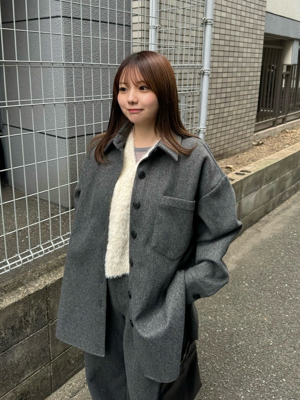 グレー系のカバーオール、ホワイト系のベスト、グレー系のニット/セーターを着用したレディースの秋コーディネートの4枚目の写真