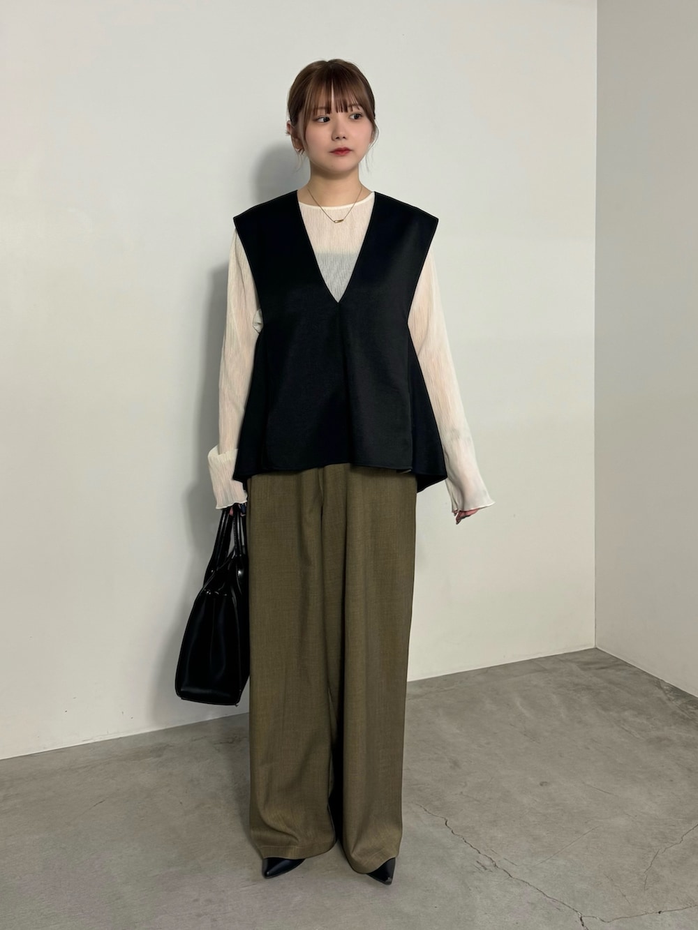 ブラック系のベスト、ブラウン系のスラックス、ホワイト系のTシャツ/カットソーを着用したレディースの冬コーディネートの2枚目の写真